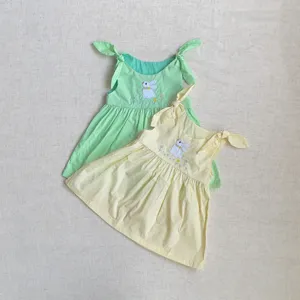 Détail de robe d'été à bretelles pour bébé avec broderie de lapin mignonne et nœuds.