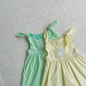 Gros plan détaillé sur la jolie broderie de lapin et bretelles nouées pour robe.