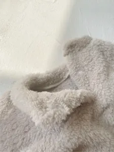 Detalle mameluco polar invierno bebé, tejido suave beige de mono grueso para niños pequeños.