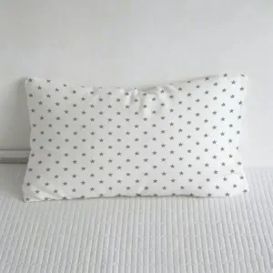 Detalle de patron de estrellas grises en cojin blanco, tela suave para cama y sofa.