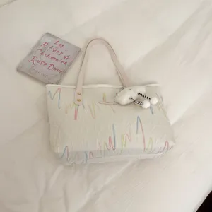 Vista detallada de un bolso de hombro casual con bordado y colgante de nube.