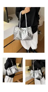 Dettaglio della borsa a spalla argentata a pois con fiocco di perle in un ambiente elegante.