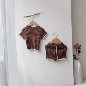 Vue détaillée de l'ensemble pull et short en tricot marron pour bébé suspendu au mur.