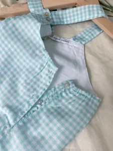 Detailed view of infant summer checkered thin cotton gauze overalls in light blue and white.