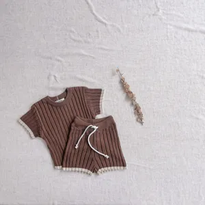 Détail haut et short tricoté bébé, tissu côtelé marron doux avec bordure beige contrastée.