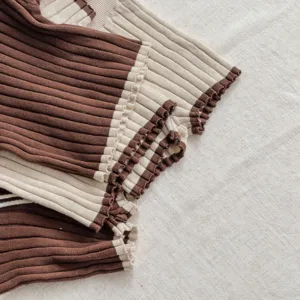 Détail tricot côtelé bébé, bordure couleur contrastée marron et beige, tissu doux respirant.