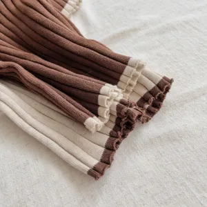 Vue rapprochée de la manchette de pull en tricot pour bébé avec bordure contrastée et élégante.