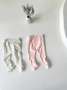 Détail de leggings bébé avec pieds, tissu doux en coton et jolie bordure en dentelle.