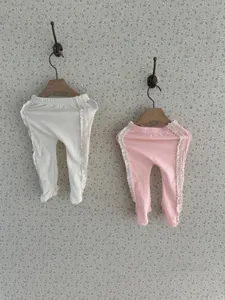 Vue détaillée de leggings bébé avec pieds et volants mignons en blanc et rose.