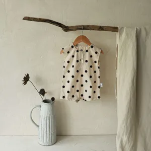Detailed view of cute baby sleeveless cotton romper with black polka dots, ideal for summer.