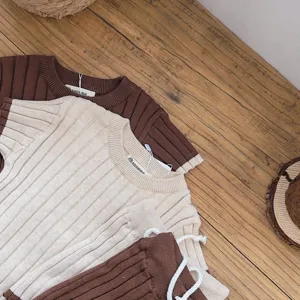 Détail ensemble pull et short tricot bébé, tenue douce avec bandes contrastées.