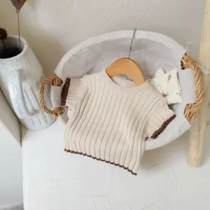Détail de pull pour bébé en tricot doux, manches courtes, bordure contrastée marron.