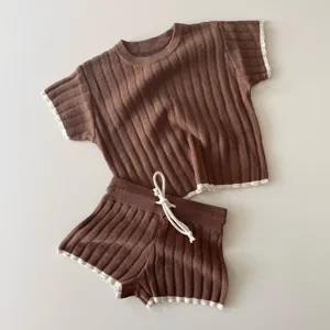 Détail de l'ensemble doux en tricot marron pour bébé haut manches courtes et short liseré.