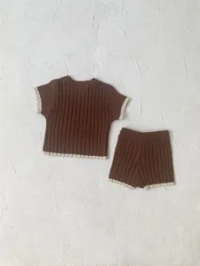Vue détaillée de l'ensemble pull tricoté et short pour bébé en marron avec des ourlets beiges.