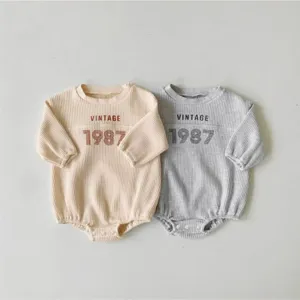 Infant waffle knit long sleeve romper with vintage 1987 print, comfortable baby bodysuit.
