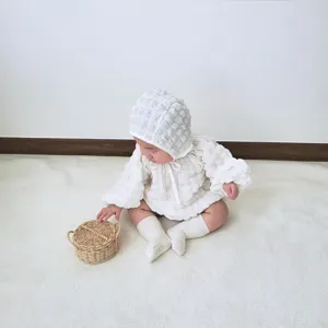 Infant bubble weave romper detail, soft white baby bodysuit close-up view in cozy lifestyle setting.