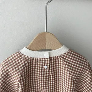 Detail view of baby brown gingham romper back collar, snap buttons, and soft cotton fabric texture.