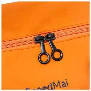 Détail de sac de voyage orange, tissu durable et doubles curseurs de fermeture éclair.