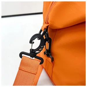 Gros plan détaillé du sac de voyage orange montrant le mousqueton et la sangle.