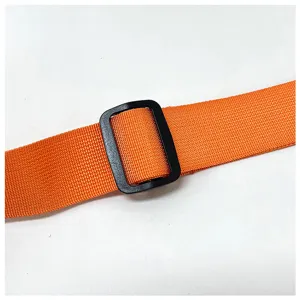 Gros plan sur la sangle de sac orange réglable avec boucle noire, détail de ceinture.