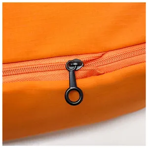 Gros plan détaillé de la fermeture éclair et du tissu résistant du sac de voyage orange.