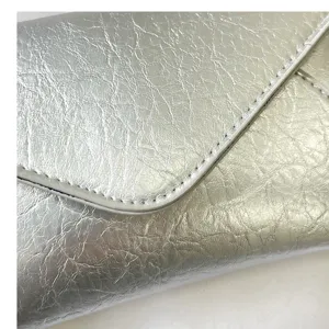 Silver metallic crinkled leather envelope shoulder bag detail showing fine stitching and flap.