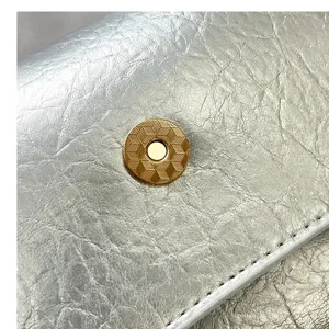 Metallic crinkled leather shoulder bag detail shot, elegant gold magnetic snap design.