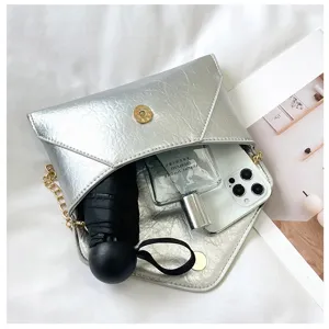 Silver metallic envelope shoulder bag detail showing interior capacity with daily items.