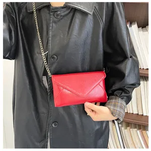 Detailed view of the red envelope shoulder bag with metal chain strap and fine leather texture.