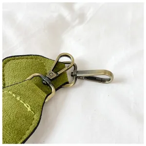 Green suede bag strap detail with bronze metal lobster clasps and hardware accessories.