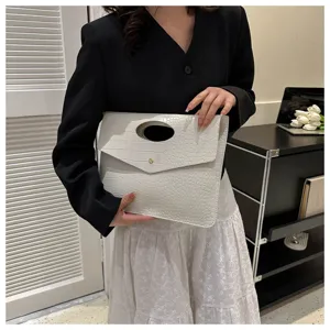 Dettaglio della stilosa borsa pochette a bustina con motivo coccodrillo e manico rotondo bianco.