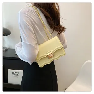 Close-up detail showing the trendy yellow wavy flap shoulder bag with sleek gold chain.