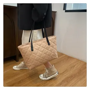 Detailed view of the quilted beige tote bag with black handles, showing texture and use.