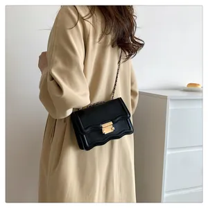 Detail view of the black wave-patterned mini flap bag with chic chain strap and gold clasp.