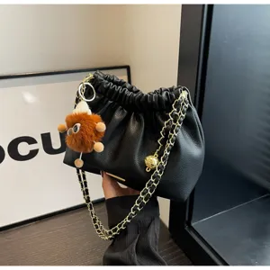 Chic black pleated bucket bag with gold chain strap and cute plush charm detail.