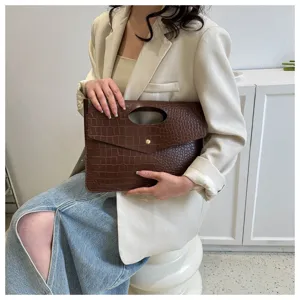 Vista dettagliata di una borsa marrone effetto coccodrillo con manico rotondo e stile retro.