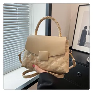 Detailed view of beige quilted flap shoulder bag with braided handle and cross-body strap.