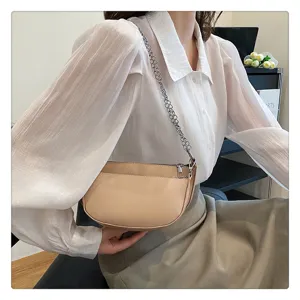 Close-up view of stylish crescent saddle shoulder bag with metallic chain strap and beige PU leather.