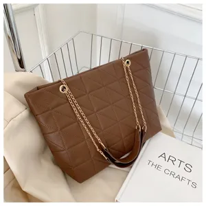 Detail shot of a brown quilted tote bag with gold chain straps, elegant design and large capacity.