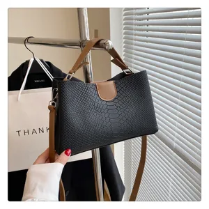 Detailaufnahme einer stilvollen schwarzen Schlangenhaut-Handtasche mit braunem Griff.