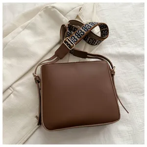 Brown crossbody bag for women with wide patterned strap, stylish commuting shoulder bag.