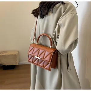 Detail view of stylish brown quilted shoulder bag, showing premium texture and metallic clasp.