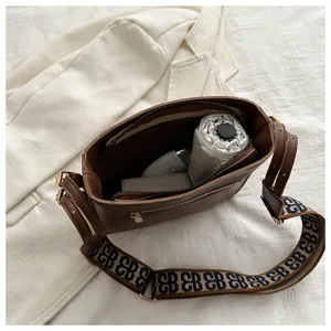 Brown bucket bag for women with wide patterned shoulder strap, large capacity daily commuting bag.