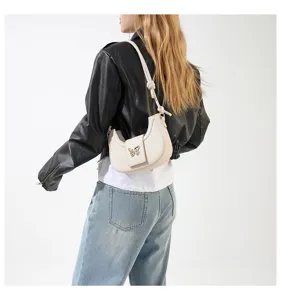 Detailed back view of a trendy white underarm hobo bag featuring a chic gold butterfly clasp.