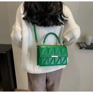 Green quilted top-handle crossbody bag detail view, stylish women shoulder bag lifestyle scene.