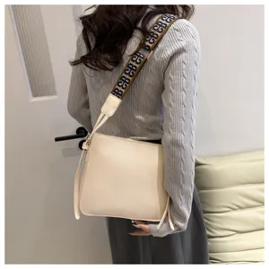 Detail view of a chic beige shoulder bag with wide patterned strap for women daily commuting.