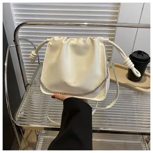Dettaglio borsa a secchiello in pelle PU bianca con tracolla a catena e chiusura.