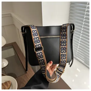 Black PU leather bucket bag with wide woven strap, stylish commuter shoulder bag for women.