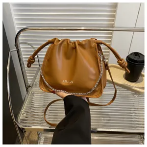 Vista dettagliata della borsa a secchiello marrone plissettata con catena metallica e coulisse.