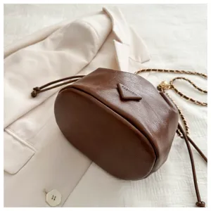 Close up detail view of brown pu leather bucket bag with triangular patch and chain strap.